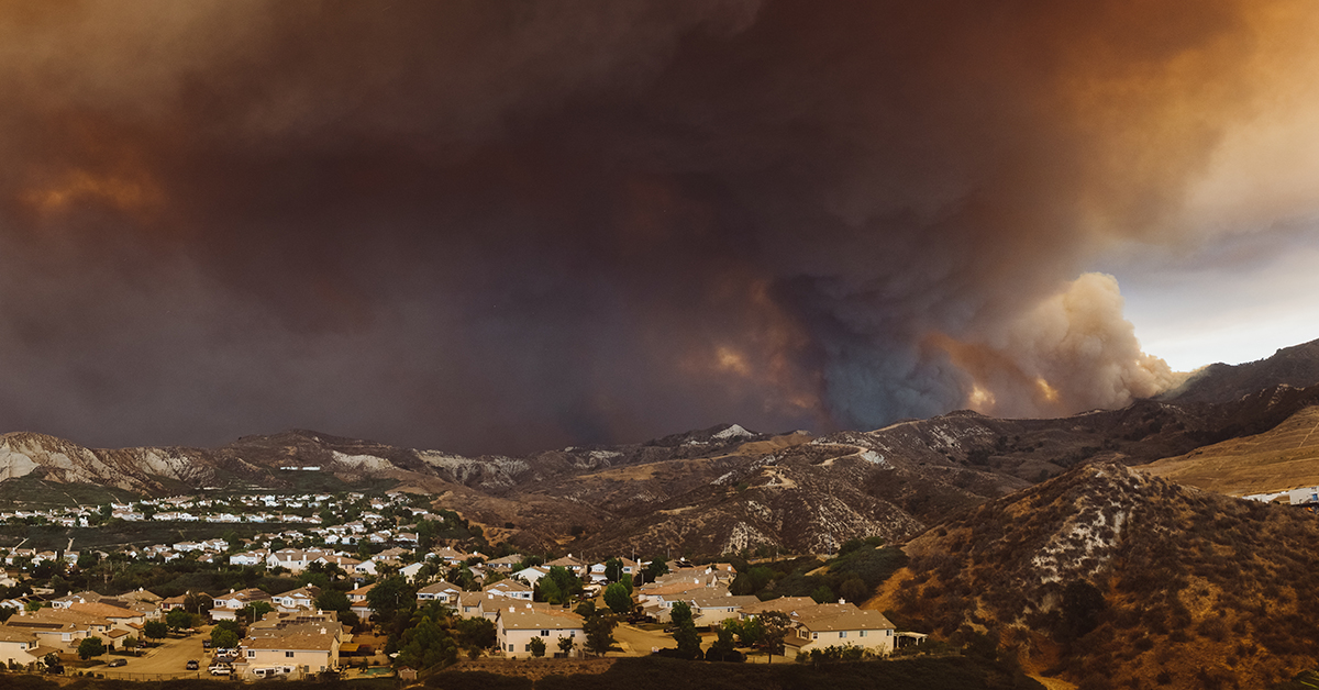 A Town with a wildfire burning behind it in the hills